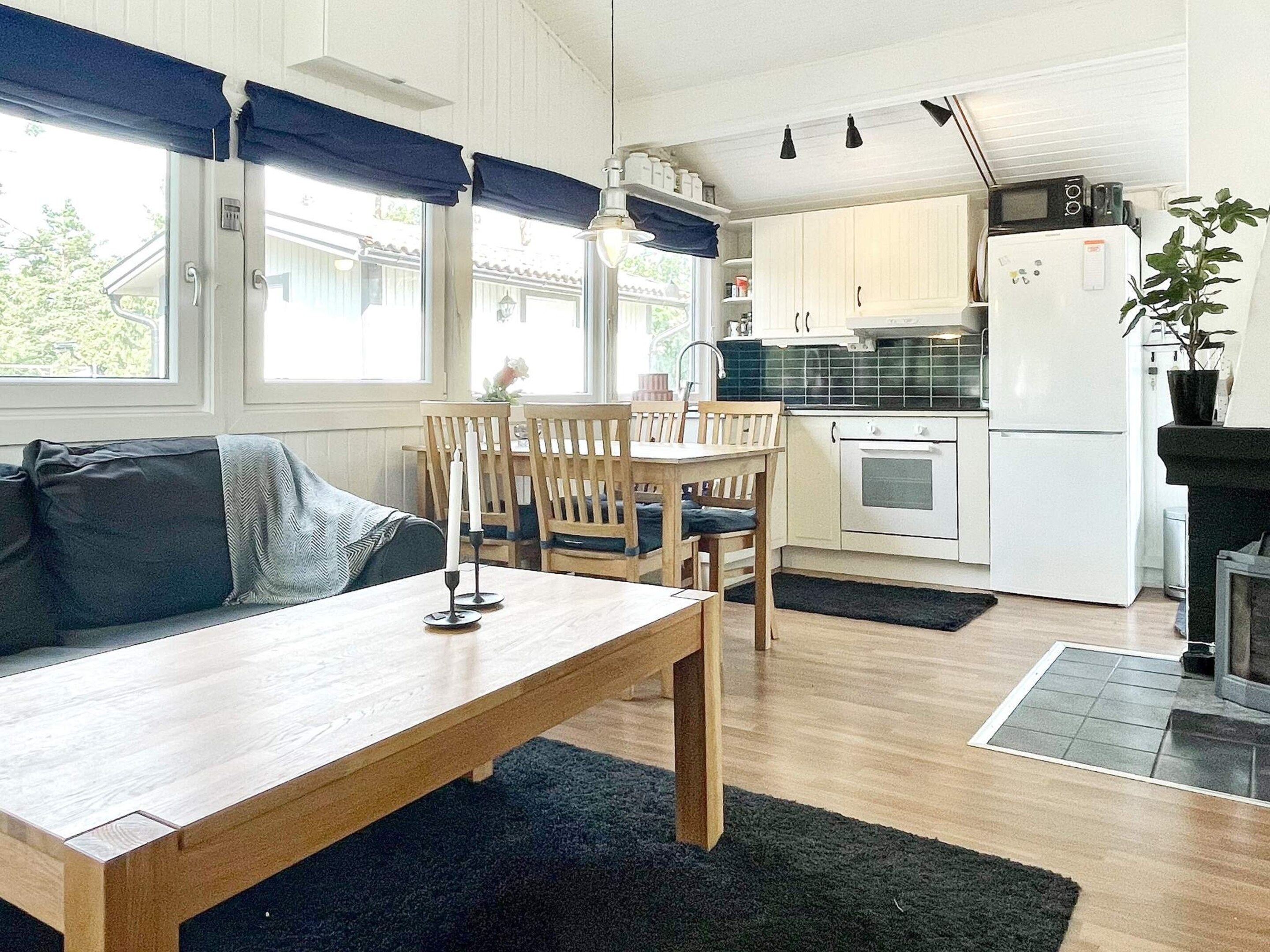 A cozy kitchen with wooden cabinets, a dining table, and a black rug.