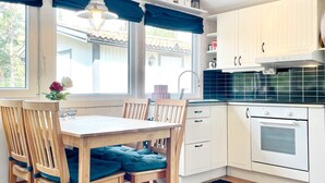 A kitchen with wooden cabinets, a white oven, and a dining table with chairs. - 6 Person Holiday Home in Monsteras (Monsteras)