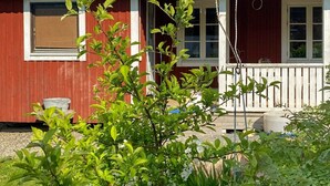 A red building with a white porch and a metal roof. - 4 Person Holiday Home in Torpshammar (Torpshammar)