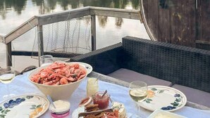 A dining table with seafood, cheese, and wine glasses, set against a view of a calm lake. - 4 Person Holiday Home in Torpshammar (Torpshammar)