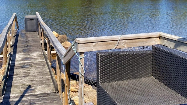 A wooden dock leading to a covered seating area by a calm lake, surrounded by dense trees. - 4 Person Holiday Home in Torpshammar (Torpshammar)