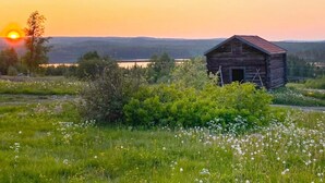 A rustic wooden barn in a field with a sunset in the background. - 4 Person Holiday Home in Torpshammar (Torpshammar)