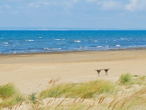 Una spiaggia con una panchina e dune in primo piano.