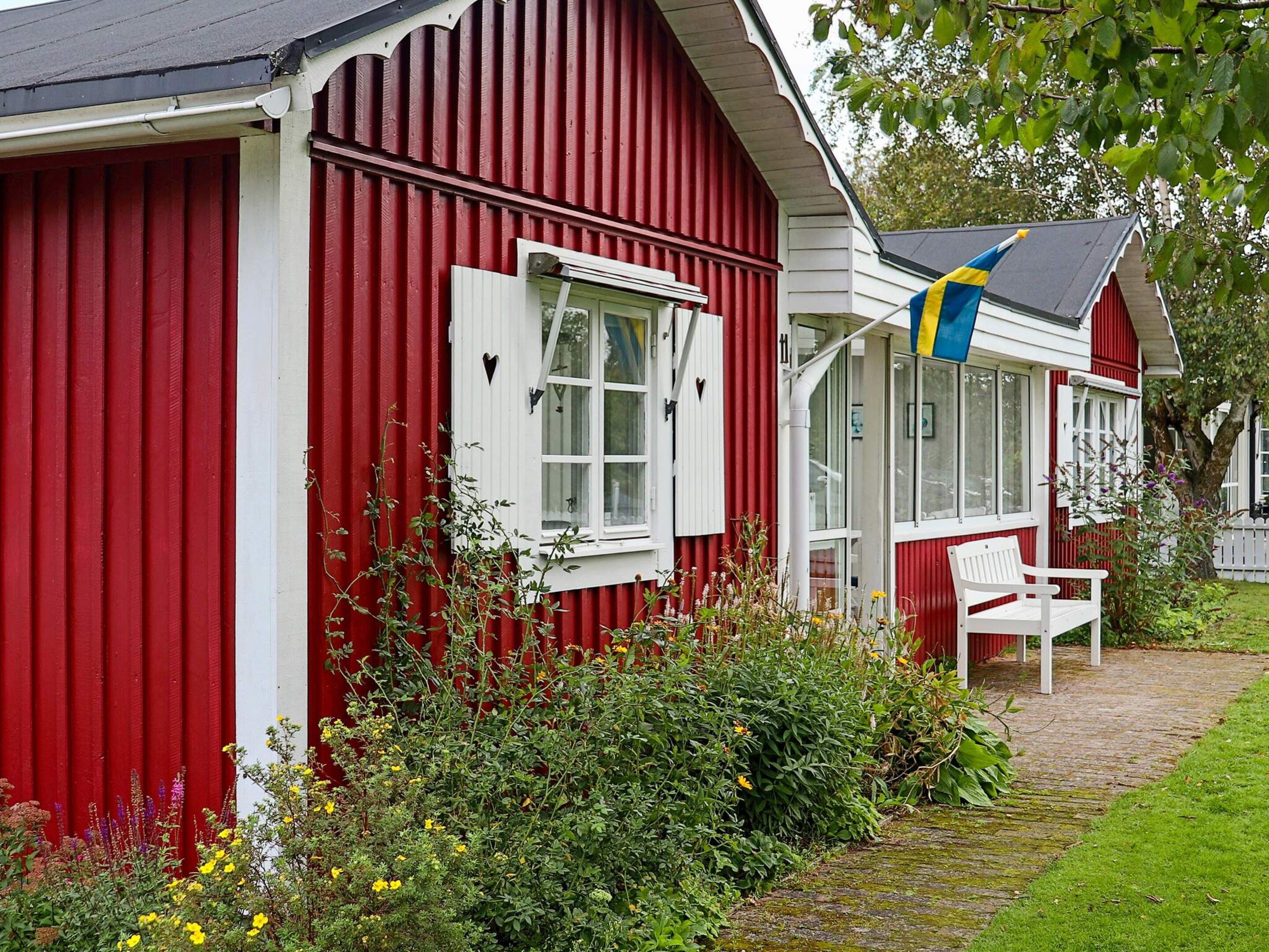 A red building with white trim, a white bench, and a flag.