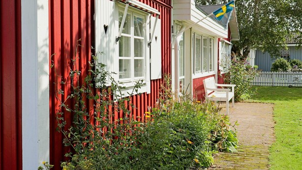 Et rødt hus med hvide detaljer, et vindue og et flag.