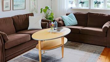 A living room with a brown sofa, a round coffee table, and a potted plant.