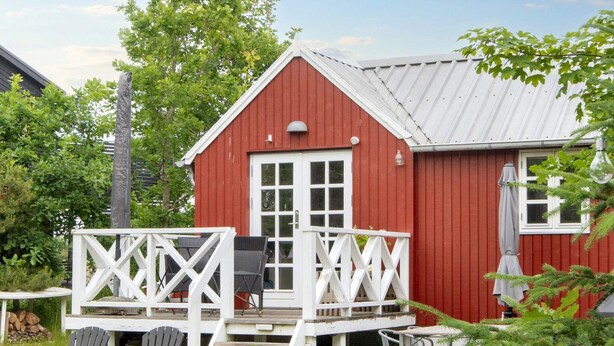 A red barn with a white porch, outdoor seating, and a covered patio area. - 4 Star Holiday Home in Grenaa (Grenaa)