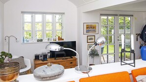 A living room with a television, a desk with a computer, and a large window with multiple panes. - 4 Star Holiday Home in Grenaa (Grenaa)