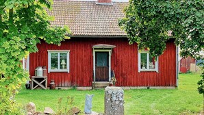 A red wooden house with a tiled roof, a front door, and windows. - 4 Person Holiday Home in Mariestad (Mariestad)