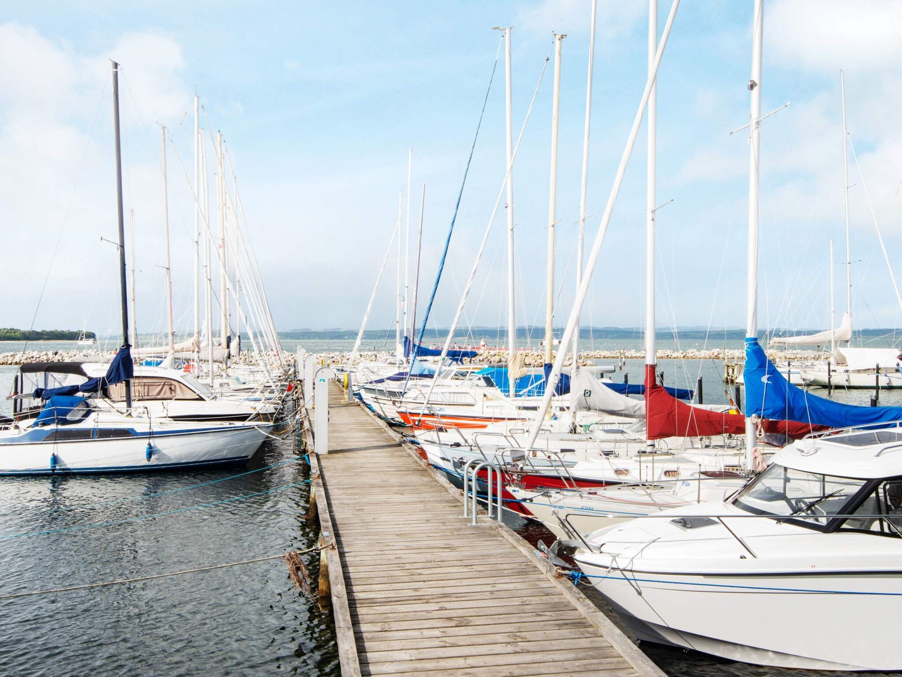 A marina with multiple boats docked along a wooden pier.