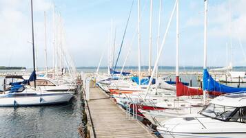 A marina with multiple boats docked along a wooden pier.