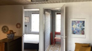 A room with a bed, a desk, and a chair. There is a door leading to another room. - 4 Star Holiday Home in Ebeltoft (Ebeltoft)