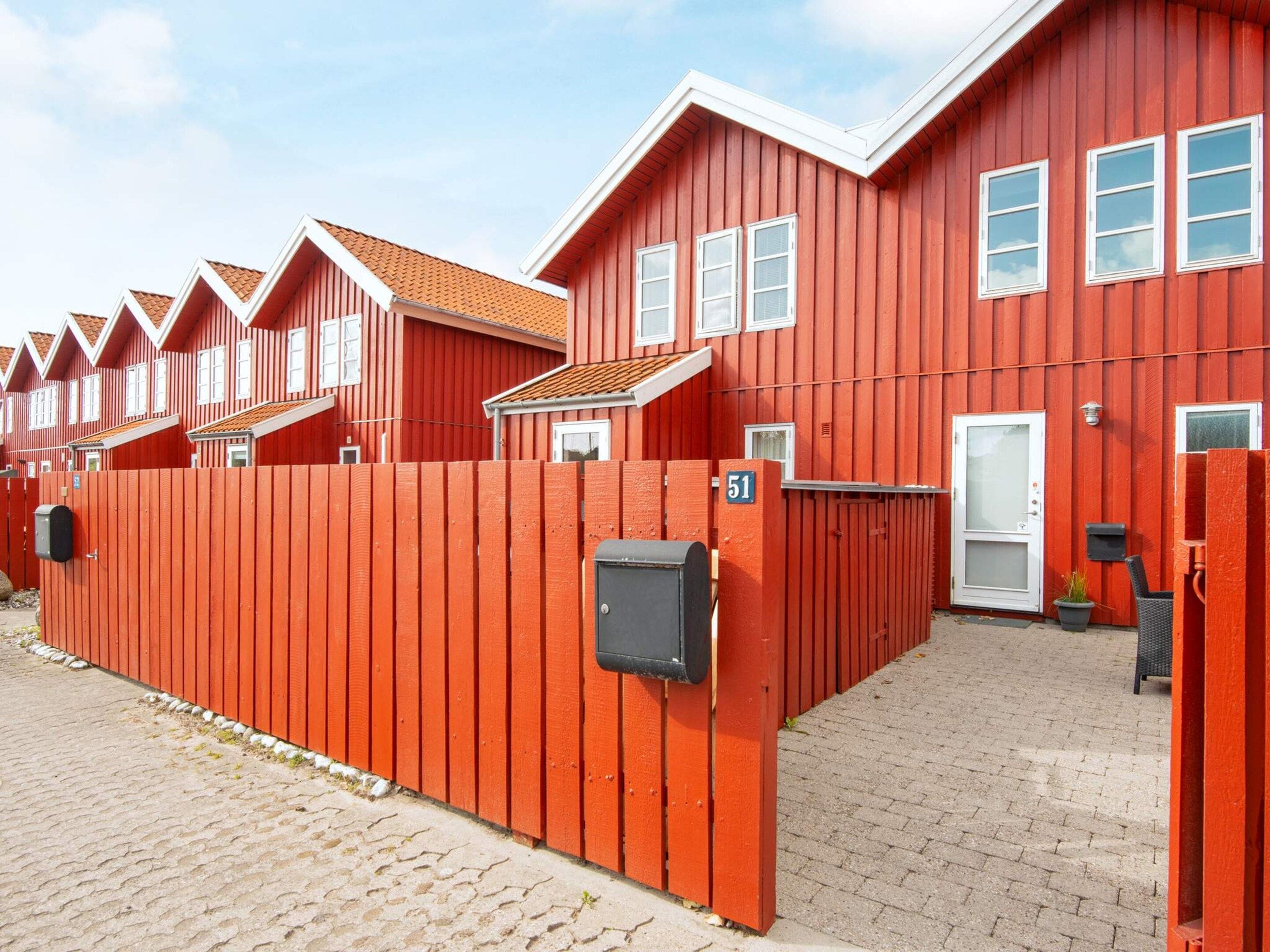 A row of red buildings with a brick pathway leading to a gate marked with the number 51.