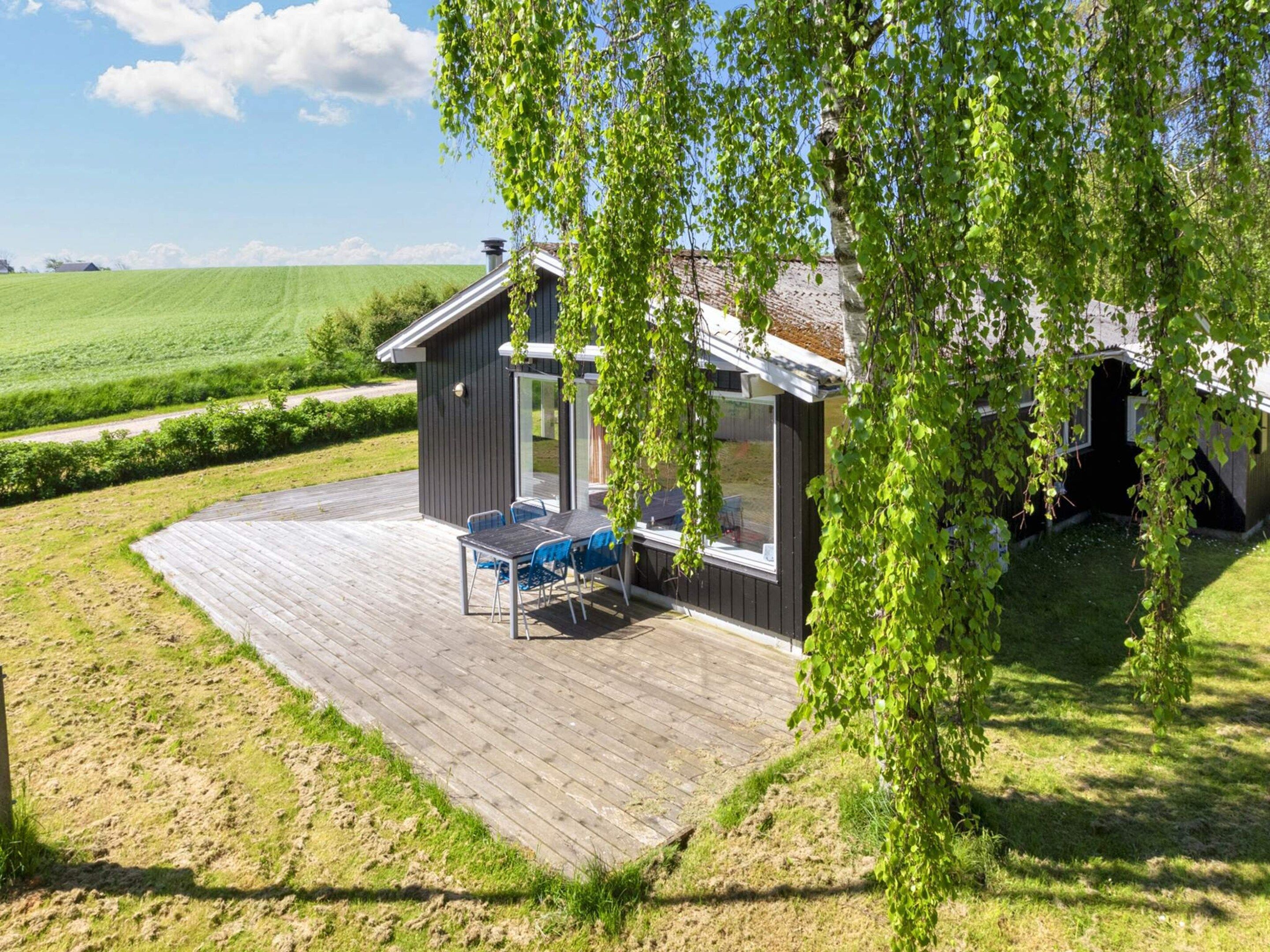 Een modern huis met een terras, een glazen deur en uitzicht op het landschap.
