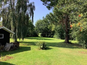 A grassy outdoor area with a small shed, trees, and a clear sky. - 6 Person Holiday Home in Nykobing M (Nykobing Mors)