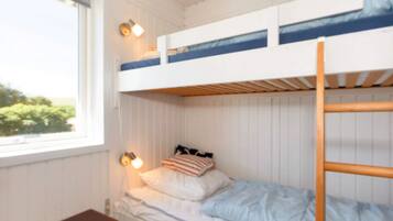 A bunk bed with a wooden ladder, a bedside table, and a window with a view of greenery.