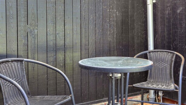 Eine Terrasse mit zwei Metallstühlen und einem kleinen runden Tisch.