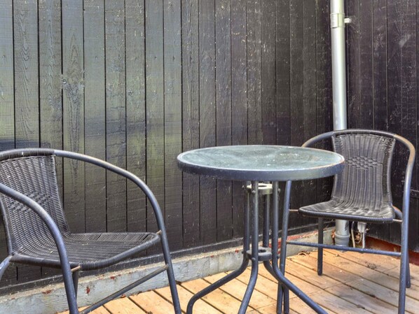 Un patio con dos sillas de metal y una pequeña mesa redonda.