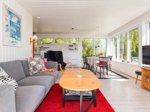 A modern living room with a grey sofa, red rug, wooden coffee table, and a dining area with a table and chairs. - 6 Person Holiday Home in Nykobing M (Nykobing Mors)