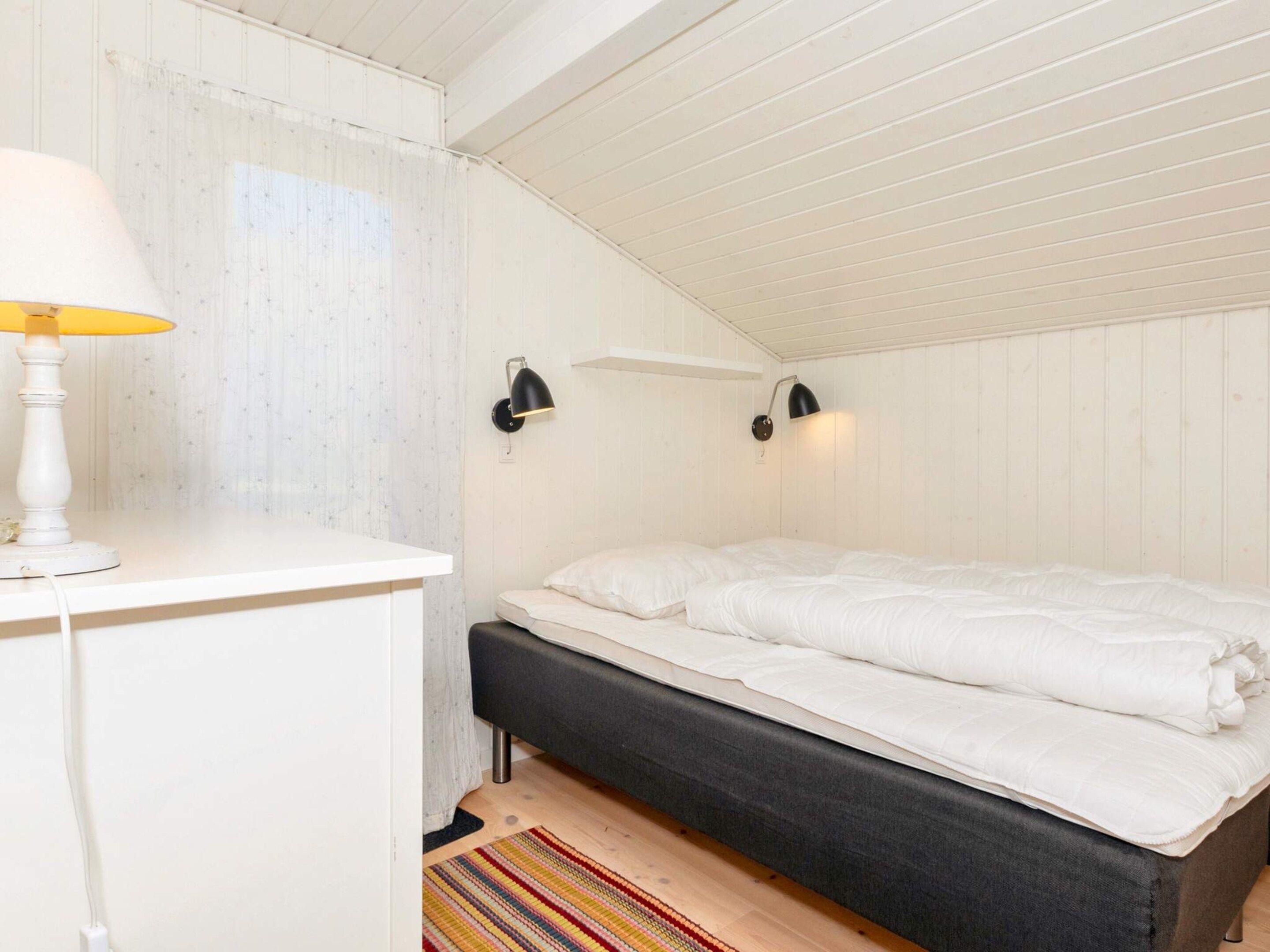 Ett sovrum med en s äng, sänglampor, ett skrivbord och en matta.