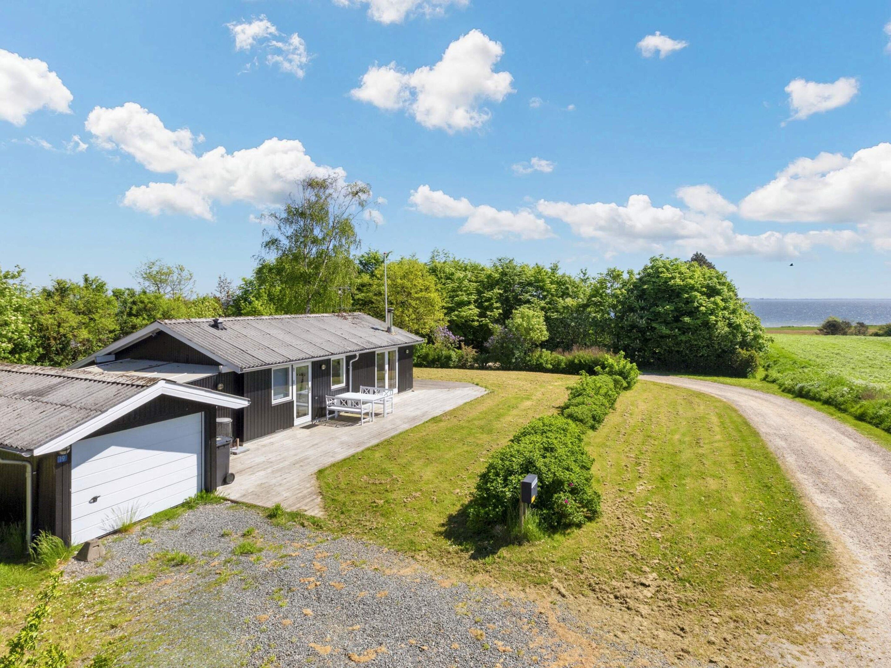 Een gelijkvloers huis met garage, overdekte veranda en een grindpad.