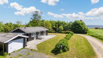 Een gelijkvloers huis met garage, overdekte veranda en een grindpad.