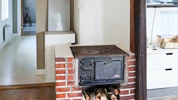 A room with a brick stove, a white cabinet, and a wooden floor.