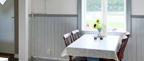 Un comedor con una mesa, sillas, un ventanal y un panel eléctrico en la pared.
