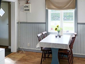 Spiseområde med bord, stole, et vindue med udsigt og et fastmonteret eltavle.