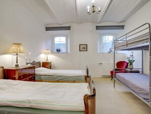 Habitació amb dos llits, un taulell, una làmpada, un radiador i una finestra amb vistes.