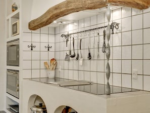 A kitchen with white tiles, hanging utensils, and a wooden beam above the counter. - 5 Star Holiday Home in Spottrup (Spøttrup)