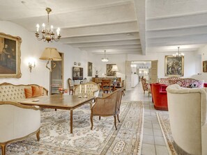 A spacious living room with a dining area, featuring a chandelier, a large painting, and a red sofa. - 5 Star Holiday Home in Spottrup (Spøttrup)