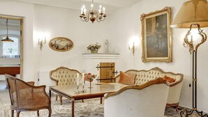 A room with a dining table, chairs, a sofa, a chandelier, wall-mounted lamps, and a fireplace. - 5 Star Holiday Home in Spottrup (Spøttrup)