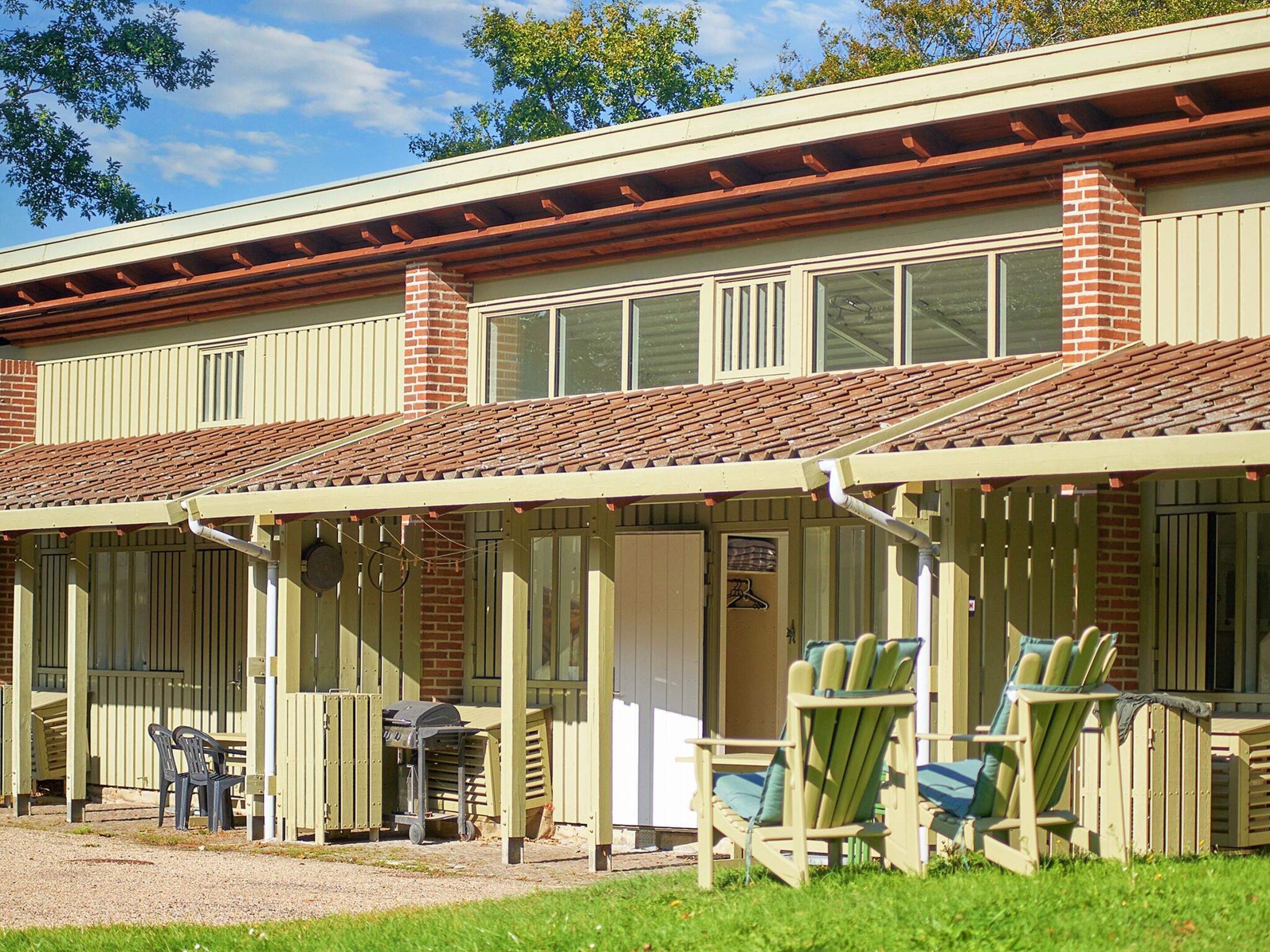 A building with a covered patio area, outdoor seating, and a brick chimney.