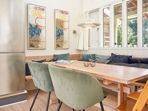 A modern kitchen with a wooden dining table, two green upholstered chairs, and a stainless steel refrigerator. - 5 Person Holiday Home in Allinge (Allinge)