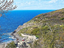 Un paysage côtier caractérisé par une rive rocheuse, un sentier de terre et une végétation clairsemée.