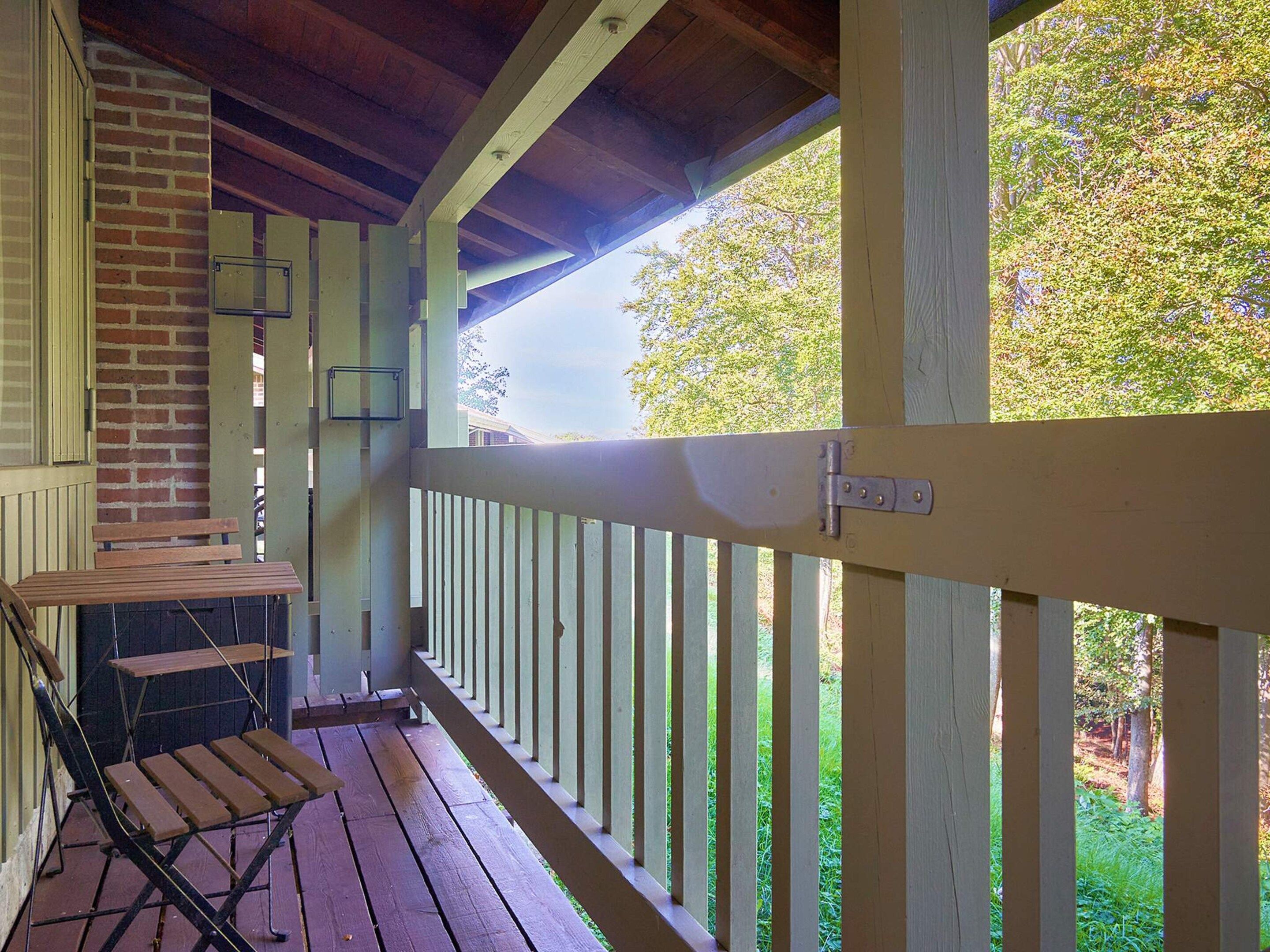 A wooden deck with a bench and a grill, overlooking a grassy area.