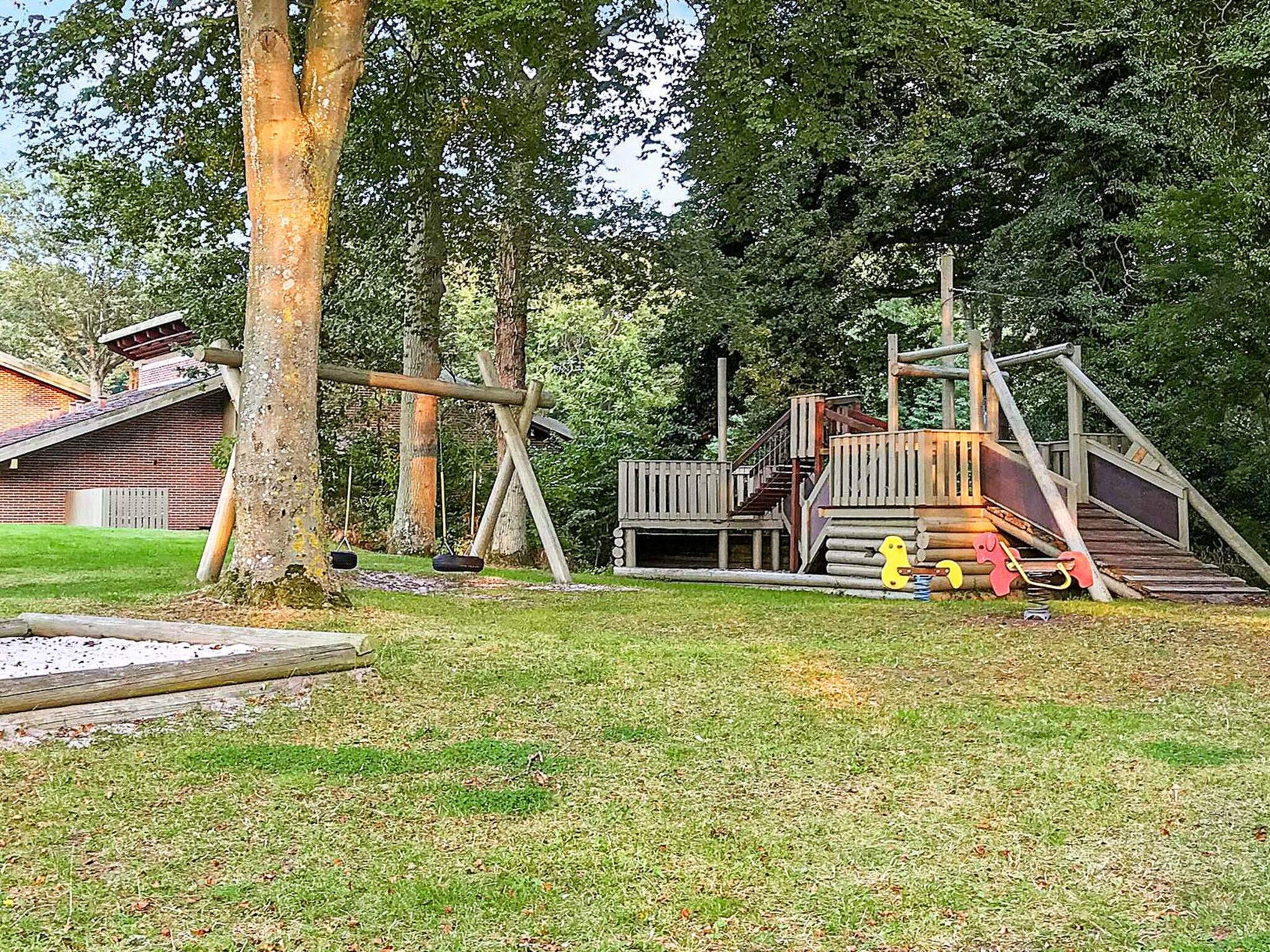 A playground with a wooden swing set, a slide, and a small climbing structure.