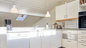 Une cuisine moderne avec des armoires blanches, des appareils en acier inoxydable et des luminaires suspendus.