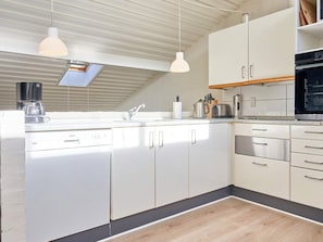 A modern kitchen with white cabinets, stainless steel appliances, and pendant lighting. - 5 Person Holiday Home in Allinge (Allinge)