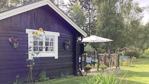 A wooden cabin with a window, a porch, and a garden. - 4 Star Holiday Home in Rimbo (Rimbo)