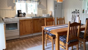 A kitchen with wooden cabinets, a stove, a dining table with chairs, and a hanging light fixture. - 4 Star Holiday Home in Rimbo (Rimbo)