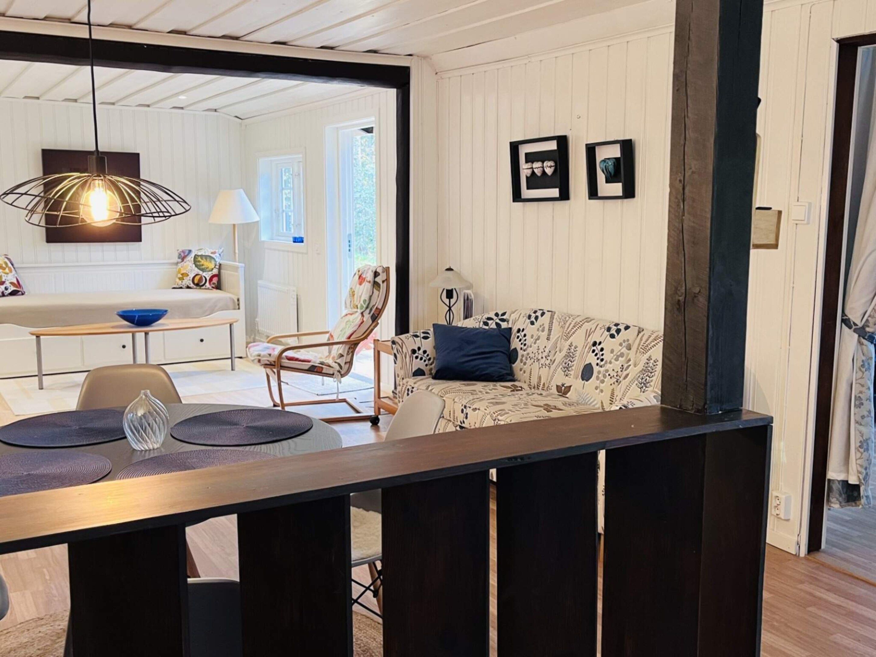 Una sala de estar moderna con comedor, un sofá, una silla y una mesa con lámpara.