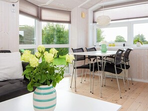 Eine moderne Küche mit Essbereich, mit einem weißen Tisch, schwarzen Stühlen und einer Vase mit Blumen.