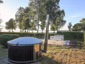A hot tub with a metal pole, surrounded by a grassy area and a bench. - 5 Person Holiday Home in Stubbekobing (Stubbekobing)
