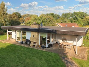 Une maison moderne dotée d’un patio, d’un espace salon extérieur et d’une cheminée en briques.