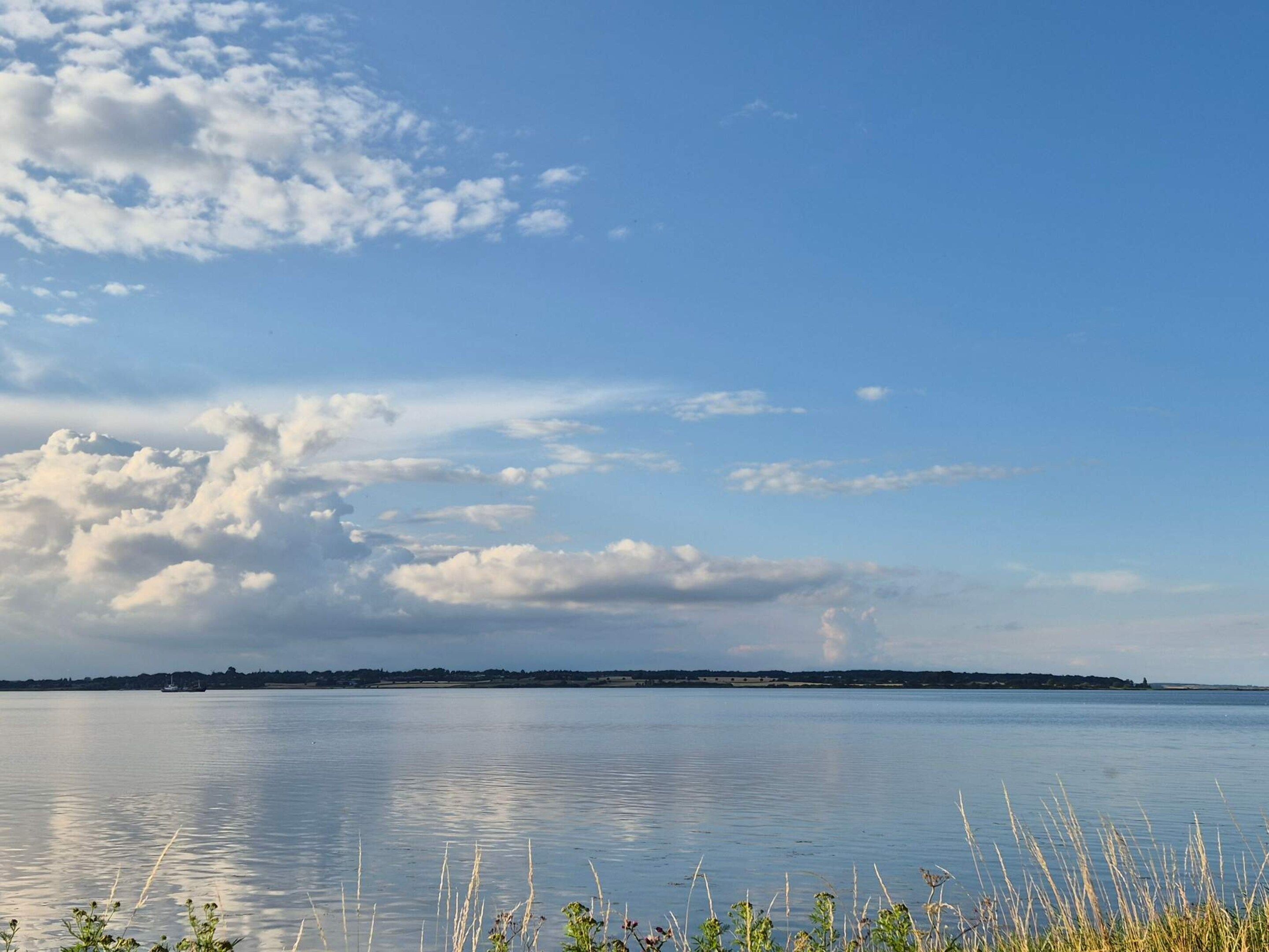 A calm body of water with a distant shoreline and a clear sky.