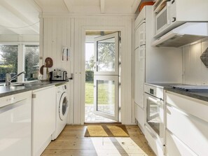 Une cuisine de taille réduite équipée d’un lave-linge, d’un évier et d’une cuisinière.