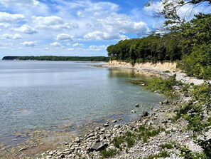 Un lac paisible, bordé d’une rive rocheuse, avec une forêt dense en arrière-plan.
