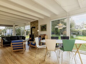 A modern living room with a fireplace, wooden flooring, and large windows offering a view of the outdoors. - 5 Person Holiday Home in Stubbekobing (Stubbekobing)